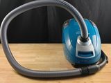 a blue and silver vacuum sitting on a wooden table