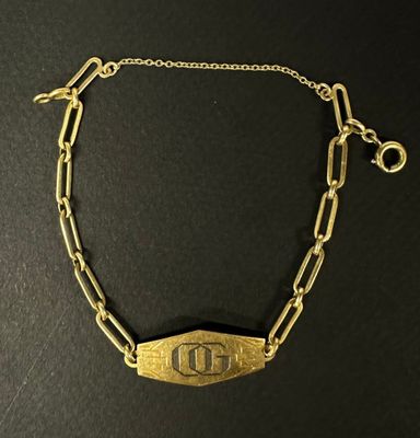 un gros plan sur un bracelet à chaîne en or orné de la lettre « d »