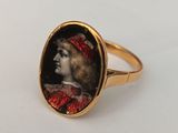 a close up of a gold ring with a picture of a woman wearing a red hat