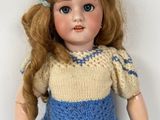 a doll that is wearing a blue dress and a yellow sweater