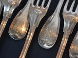 a lot of silver spoons and forks on a black table