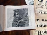 a book open on a table with a bunch of newspapers on it