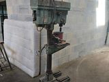 a drill on a stand in a room with a brick wall
