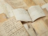 several old letters and old papers are piled together on a table