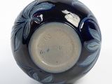 a black vase with blue flowers on it on a white surface