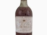 une vieille bouteille de vin posée sur une surface blanche