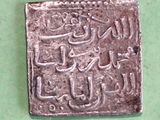 an old silver coin with arabic writing on it sitting on a green surface