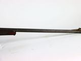 an old gun is sitting on a white surface next to a glass holder