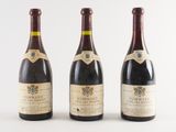 three bottles of wine are lined up on a white surface