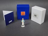 a small figurine of a woman standing in front of a box