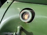 a close up of a green vehicle with a rusted door handle