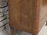 a wooden cabinet with a glass door and a stone wall behind it