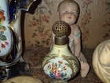 a small doll sitting on a table next to a vase and other items