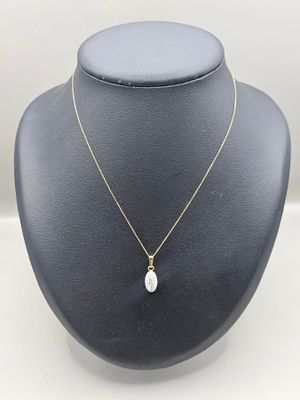 a gold necklace with a white pearl pendant on a mannequin
