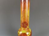 un vase orange posé sur un socle en bois