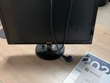 a computer monitor sitting on a desk with a magazine next to it