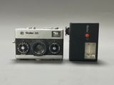 an old camera with a flash drive next to it on a white surface