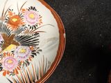 a plate with a painting of a bird and flowers on it