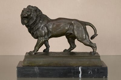 statue en bronze représentant un lion, posée sur un socle en marbre, elle-même posée sur une table