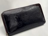 Le portefeuille Louis Vuitton est noir et muni d'une fermeture éclair dorée.