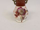 a small vase with a flower on it on a white surface