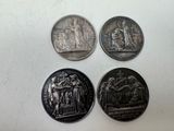 quatre types différents de pièces d'argent sur une surface blanche