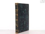 an old book sitting on top of a table next to a white wall