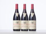 three bottles of red wine sitting on top of a table