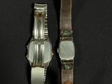 two watches sitting next to each other on a black surface