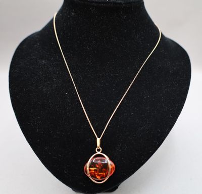 un collier avec un pendentif en verre orange sur un mannequin noir
