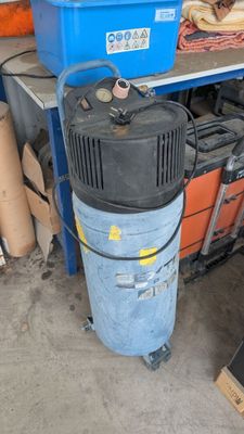 a blue and black air compressor next to a stack of boxes