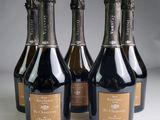 four bottles of champagne are lined up on a table