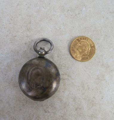 a small silver pocket watch next to a gold coin