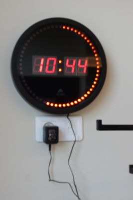 une horloge accrochée au mur, à laquelle sont reliés des fils