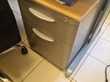 a desk with a file cabinet and a chair in the corner