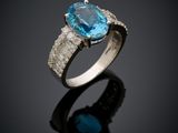 a blue topaze and diamond ring on a black surface