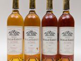quatre bouteilles de vin sont alignées sur une surface blanche