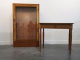 une petite table sur laquelle est posé un miroir, à côté d'une autre petite table avec une chaise