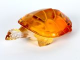 an orange glass turtle figurine sitting on a white surface