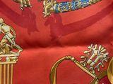 an image of a red and gold scarf with a picture of a man on a horse