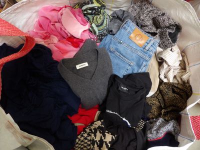 a large bag full of clothes and clothes sitting on a bed