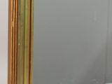 a gold framed mirror sitting on a white surface