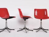 three red chairs sitting next to each other on a white surface