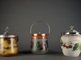 trois bocaux en verre avec leurs couvercles sont alignés sur une surface grise
