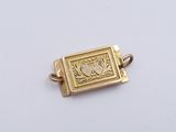 an image of a gold plated book charm on a white surface