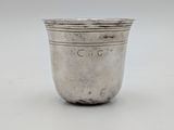an old silver cup with a handle on a white surface