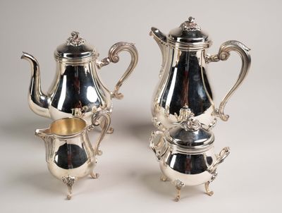 deux théières en argent et une cafetière posées sur une table