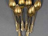 six spoons are arranged in a row on a gray surface
