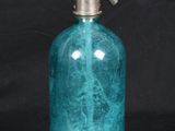 blue glass soap dispenser with a metal pump on a black background