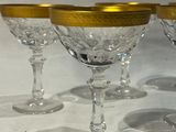 quatre verres à vin aux bords dorés sont posés sur une table blanche